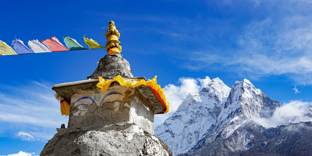 Buddhist stupa and snow covered Himalayan peaks on the Everest Base Camp trekking route in Nepal